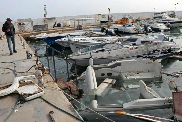 A man inspects damaged boats at the site of an Israeli strike in the port of the Lebanese coastal city of Tyre on April 4, 2026. The Israeli military said on April 3, it had struck more than 3,500 targets across Lebanon in the month since fighting with Iran-backed Hezbollah militants. Lebanon was drawn into the Middle East war on March 2 when Hezbollah launched attacks on Israel to avenge the killing of the Iranian leader. Israel has responded with broad strikes across Lebanon and a ground offensive. (Photo by Kawnat HAJU / AFP)