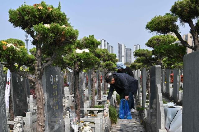 People pay their respects at a cemetery on the eve of the Qingming festival, also known as the Tomb-Sweeping festival, in Shanghai on April 4, 2026. (Photo by Hector RETAMAL / AFP)