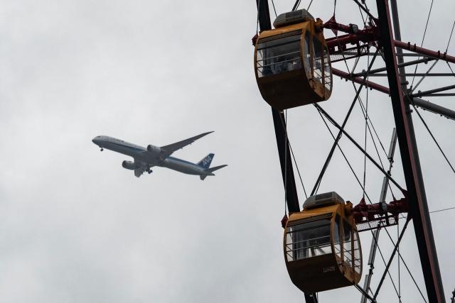 People ride on the Diamond and Flower ferris wheel as at Kasai Rink park, as an ANA plane lands, as a large storm moves over Tokyo on April 4, 2026. (Photo by ANDREW CABALLERO-REYNOLDS / AFP)