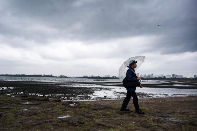 A man uses an umbrella in the rain as he walks along the beach at Kasai Rink park as a large storm moves over Tokyo on April 4, 2026. (Photo by ANDREW CABALLERO-REYNOLDS / AFP)