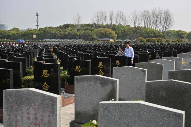 People walk at a cemetery on the eve of the Qingming festival, also known as the Tomb-Sweeping festival, in Shanghai on April 4, 2026. (Photo by Hector RETAMAL / AFP)