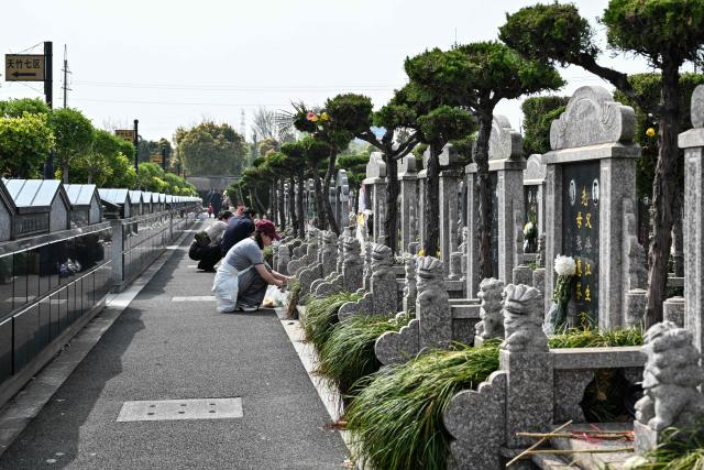 People pay their respects at a cemetery on the eve of the Qingming festival, also known as the Tomb-Sweeping festival, in Shanghai on April 4, 2026. (Photo by Hector RETAMAL / AFP)