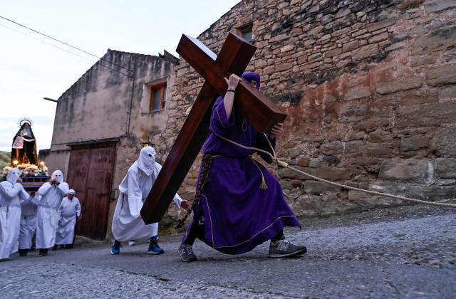 A penitent of 'La Vera Cruz' brotherhood, with a rope tied to his body, bears a cross during the Holy Friday procession in the Spanish Navarre village of Torres del Rio on April 3, 2026. Christian believers around the world mark the Holy Week of Easter in celebration of the crucifixion and resurrection of Jesus Christ. (Photo by ANDER GILLENEA / AFP)