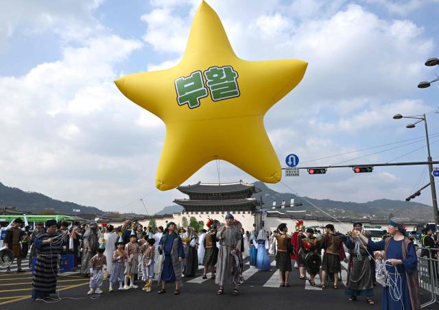 Participants in costumes carry a star-shaped balloon reading "Resurrection" as they take part in an Easter parade at Gwanghwamun Square in Seoul on April 4, 2026. (Photo by Jung Yeon-je / AFP)