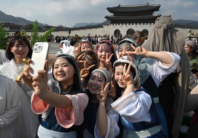 Participants in costumes take a selfie as they attend an Easter parade at Gwanghwamun Square in Seoul on April 4, 2026. (Photo by Jung Yeon-je / AFP)