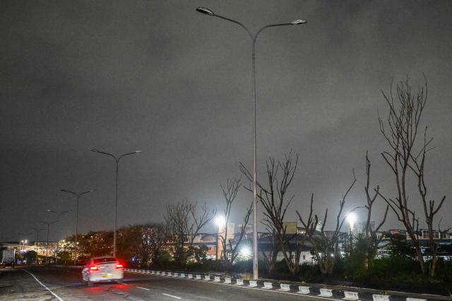 Vehicles move past switched-off street lights along a flyover in Colombo on April 2, 2026. President Anura Kumara Dissanayake has rationed fuel, raised its price by a third and increased electricity tariffs by up to 40 percent since the Middle East war disrupted global energy supplies. (Photo by Ishara S. KODIKARA / AFP)