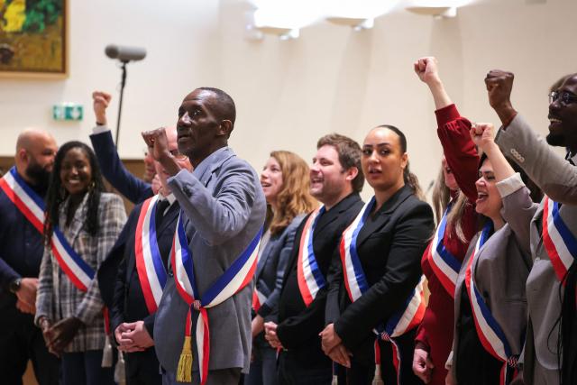 TOPSHOT - Saint-Denis Mayor Bally Bagayoko (front C) sings the French national anthems with members of city council members during a municipal council meeting at the city hall in Saint-Denis, in the outskirts of Paris, on April 4, 2026. (Photo by Thomas SAMSON / AFP)