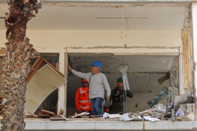 People assess the damage in a building that was hit by an Iranian strike in a residential neighbourhood in Ramat Gan on April 4, 2026. The Israeli army said on April 4 its air defences were working to down missiles fired from Iran, which medics reported wounded one person. (Photo by Jack GUEZ / AFP) / 