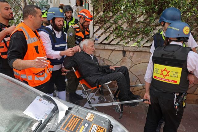 Israel's first responders evacuate a wounded person from the site of an Iranian strike that hit a residential neighbourhood in Ramat Gan on April 4, 2026. The Israeli army said on April 4 its air defences were working to down missiles fired from Iran, which medics reported wounded one person. (Photo by Jack GUEZ / AFP) / 