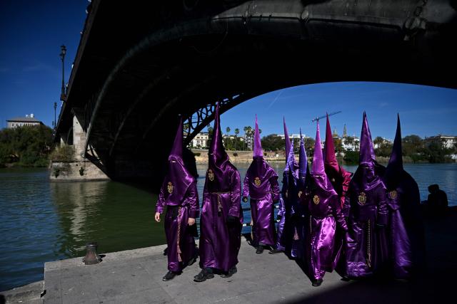 TOPSHOT - Penitents of the ‘La O’ brotherhood walk under Triana bridge before taking part in a procession during Holy Week in Seville, on April 3, 2026. Christian believers around the world mark the Holy Week of Easter in celebration of the crucifixion and resurrection of Jesus Christ. (Photo by CRISTINA QUICLER / AFP)