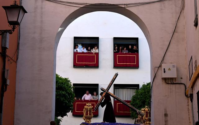 Residents watch as members of ‘La O’ brotherhood carry a float with an effigy of Christ during Holy Week processions in Seville, on April 3, 2026. Christian believers around the world mark the Holy Week of Easter in celebration of the crucifixion and resurrection of Jesus Christ. (Photo by CRISTINA QUICLER / AFP)