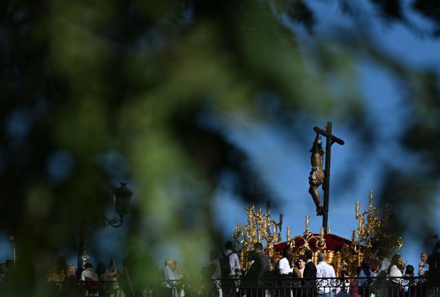 Penitents of the ‘El Cachorro’ brotherhood carry an effigy of Christ on Triana bridge during Holy Week processions in Seville, on April 3, 2026. Christian believers around the world mark the Holy Week of Easter in celebration of the crucifixion and resurrection of Jesus Christ. (Photo by CRISTINA QUICLER / AFP)
