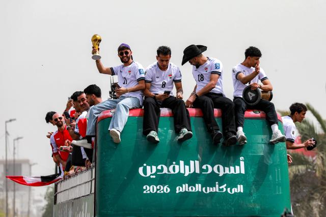 Members of Iraq's men's national football team sit atop a double-decker bus as they are paraded with fans in the Jadriya area of central Baghdad on April 4, 2026 to celebrate the country's qualification to the 2026 FIFA World Cup to be held in North America in the summer. The "Lions of Mesopotamia" secured the country's first World Cup appearance since the 1986 competition in Mexico with a 2-1 win over Bolivia late on March 31. The build-up to the match had been overshadowed by the outbreak of the Middle East war in late February, when the US and Israel attacked Iran, subsequently dragging Iraq into the conflict. (Photo by MURTAJA LATEEF / AFP)