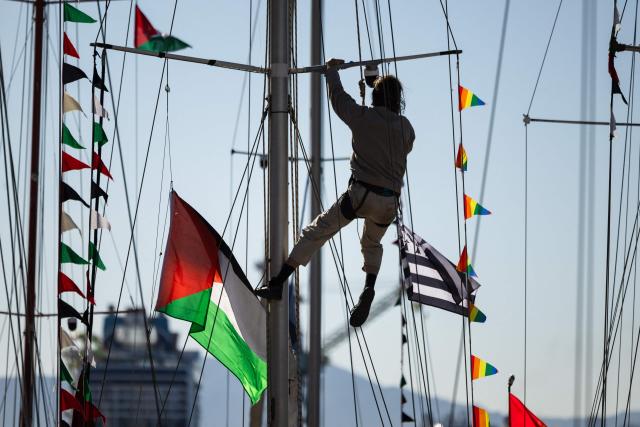 An activist climbs the mast of a boat displaying a Palestinian flag in l'Estaque, part of Marseille's harbour, southern France, on April 4, 2026, during a rally in support of a flotilla carrying activists from “Thousand Madleens to Gaza” movement as they prepare to set sail. (Photo by CLEMENT MAHOUDEAU / AFP)