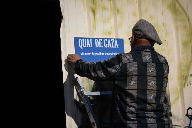 An activist hangs a sign reading “Gaza Quay” in l'Estaque, part of Marseille's harbour, on April 4, 2026, during a rally in support of a flotilla carrying activists from “Thousand Madleens to Gaza” movement as they prepare to set sail. (Photo by CLEMENT MAHOUDEAU / AFP)