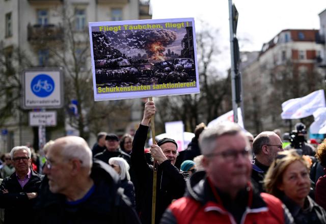 A protestester holds a sign reading "Fly dove, fly, sanction rogue state" during an Easter March Peace demonstration organised by the Berlin Peace Coordination (FRIKO) in Berlin, on April 4, 2026. (Photo by Tobias SCHWARZ / AFP)
