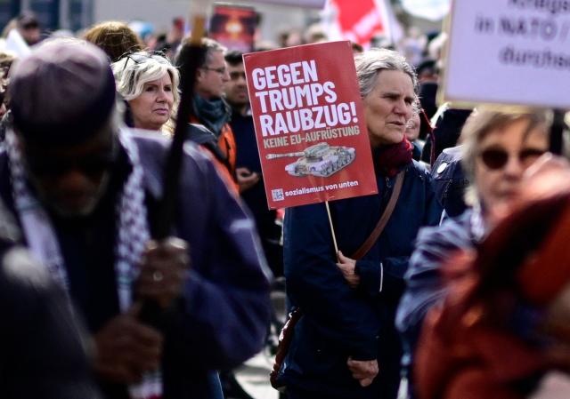 A protestester holds a sign reading "Against Trump's raid" during an Easter March Peace demonstration organised by the Berlin Peace Coordination (FRIKO) in Berlin, on April 4, 2026. (Photo by Tobias SCHWARZ / AFP)