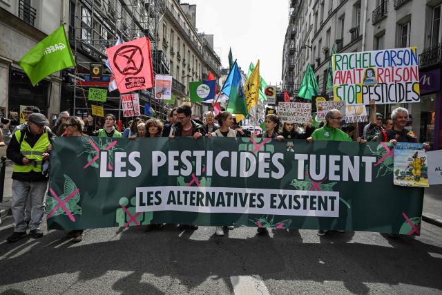 Protesters with a banner reading "Pesticides kill: alternatives exist" take part in the rally 'Marche Printemps Bruyant 2026', a mobilization against the use of pesticides, just a few days before World Health Day, in Paris on April 4, 2026. (Photo by Anna KURTH / AFP)