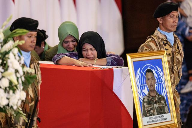 A family member of Indonesian soldier who was killed while serving with the United Nations Interim Force in Lebanon (UNIFIL) in southern Lebanon, mourns beside his coffin as the coffins of three Indonesian soldiers arrive at Soekarno-Hatta International Airport in Tangerang on April 4, 2026. Indonesia received the bodies of three peacekeepers on April 4 who were killed while on deployment in Lebanon and called for security guarantees for blue helmets a day after another three of its soldiers were injured. (Photo by Yasuyoshi CHIBA / AFP)