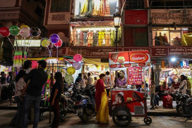 A woman buys ice-cream along a street in Varanasi on April 4, 2026. (Photo by Niharika KULKARNI / AFP)