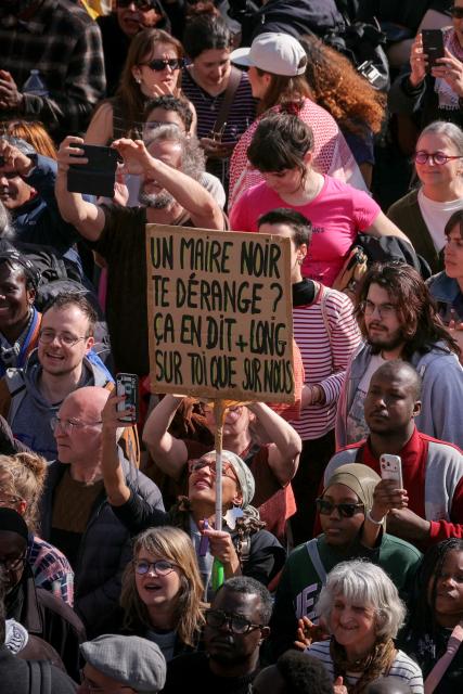 Protesters holds a placard which reads "Does a Black Mayor bother you? That says more about you than about us" as they take part in a rally outside the Saint-Denis City Hall against racism convened by Saint-Denis Mayor Bally Bagayoko, in Saint-Denis, on the outskirts of Paris, on April 4, 2026. "We want lots of Black mayors to fight the brown plague": several thousand people gathered to protest against racism on April 4, 2026 in Saint-Denis, following a call from the new LFI mayor, Bally Bagayoko, who, since his election, has been at the centre of a debate on racial discrimination that has now taken on national significance. (Photo by Thomas SAMSON / AFP)