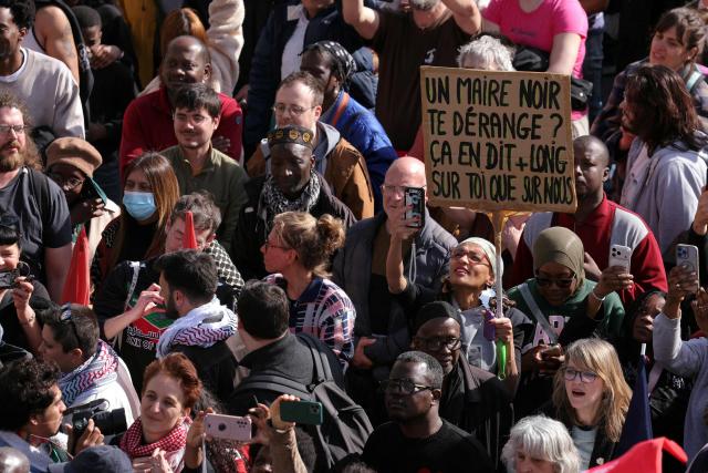 Protesters holds a placard which reads "Does a Black Mayor bother you? That says more about you than about us" as they take part in a rally outside the Saint-Denis City Hall against racism convened by Saint-Denis Mayor Bally Bagayoko, in Saint-Denis, on the outskirts of Paris, on April 4, 2026. "We want lots of Black mayors to fight the brown plague": several thousand people gathered to protest against racism on April 4, 2026 in Saint-Denis, following a call from the new LFI mayor, Bally Bagayoko, who, since his election, has been at the centre of a debate on racial discrimination that has now taken on national significance. (Photo by Thomas SAMSON / AFP)