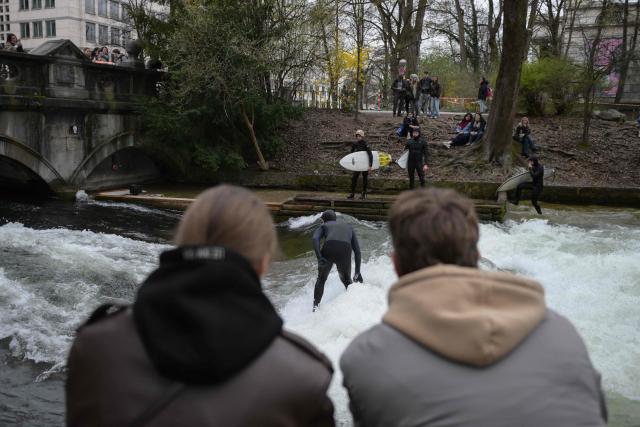 Surfers check out the famous Eisbach wave (Eisbachwelle) in the English Garden (Englischer Garten) in Munich, southern Germany, on April 4, 2026. The Eisbach wave, beloved by surfers worldwide, was flattened following river cleaning operations, authorities announced on November 4, 2025 and is now set to return. (Photo by Markus FISCHER / AFP)