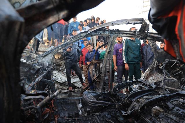 TOPSHOT - Palestinians inspect a vehicle targeted by an Israeli strike in Maghazi camp for Palestinian refugees in the central Gaza Strip on April 4, 2026. Since October 10, a fragile US-sponsored truce in Gaza has largely halted the fighting between Israeli forces and Hamas, but both sides have alleged frequent violations. (Photo by Eyad Baba / AFP)