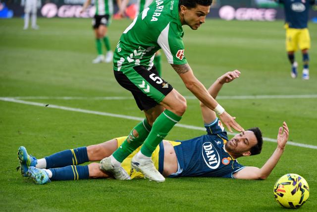 Espanyol's Spanish midfielder #08 Edu Exposito falls down next to Real Betis' Spanish defender #05 Marc Bartra during the Spanish league football match between Real Betis and RCD Espanyol at Benito Villamarin Stadium in Seville on April 4, 2026. (Photo by CRISTINA QUICLER / AFP)