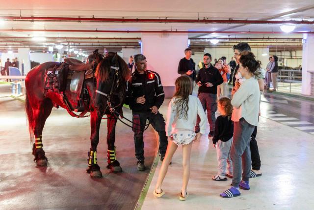 TOPSHOT - Israeli mounted police speak to people as they take cover in an underground parking used as a bomb shelter following warning sirens while intervening during a protest by left-wing activists against the ongoing war with Iran at HaBima Square in Tel Aviv on April 4, 2026. Carrying anti-war banners and chanting slogans against Prime Minister Benjamin Netanyahu, hundreds of Israelis rallied in Tel Aviv on April 4 to protest the war with Iran. Since February 28, the United States and Israel have conducted joint strikes against Iran, prompting the Islamic Republic to retaliate with daily missile barrages targeting Israel and several neighbouring countries across the region. (Photo by Ilia YEFIMOVICH / AFP) / 