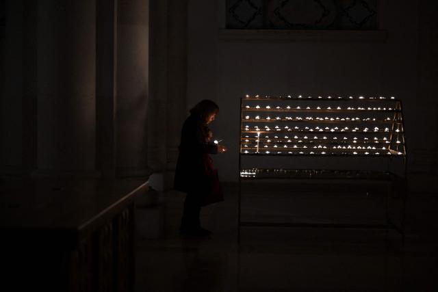 A Christian worshipper lights a candle as she attends an Easter Vigil at the Cathedral of St. Mother Teresa in Pristina, Kosovo on April 4, 2026, as part of the Holy Week celebrations. (Photo by Armend NIMANI / AFP)