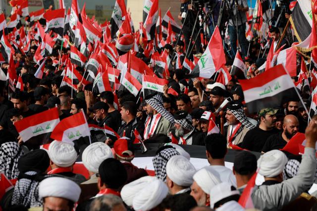 Supporters of Iraqi Shiite cleric Muqtada al-Sadr wave Iraqi flags during a demonstration in Baghdad's Tahrir Square on April 4, 2026. The protest comes following a call by Muqtada al-Sadr for his supporters to demonstrate against the United States and Israel and in condemnation of the war on Iran. (Photo by Murtaja LATEEF / AFP)