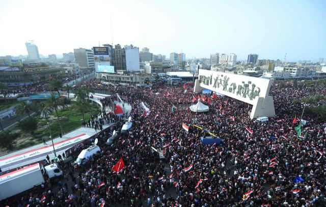 Supporters of Iraqi Shiite cleric Muqtada al-Sadr wave Iraqi flags during a demonstration in Baghdad's Tahrir Square on April 4, 2026. The protest comes following a call by Muqtada al-Sadr for his supporters to demonstrate against the United States and Israel and in condemnation of the war on Iran. (Photo by Murtaja LATEEF / AFP)