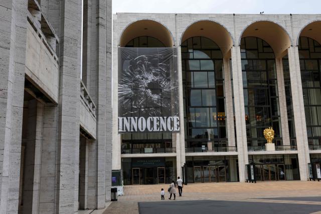 A banner of "Innocence", the final opera by the late Finnish composer Kaija Saariaho, hangs outside the Metropolitan Opera in New York on April 1, 2026. School shootings are a tragically common occurrence in the United States, but rarely do they grace the stage of one of the world's premier opera houses. But on Monday, Kaija Saariaho's "Innocence" -- which explores how a devastating attack at an international school in Finland reverberates through the lives of its survivors -- will debut at the Metropolitan Opera in New York. (Photo by ANGELA WEISS / AFP)
