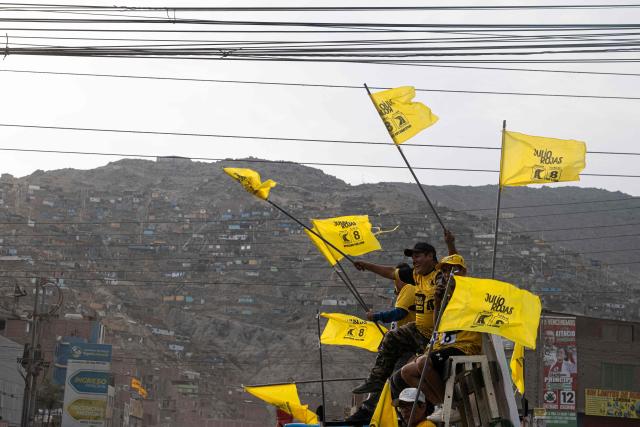 Supporters of Peru's presidential candidate Carlos Alvarez for the Pais Para Todos party wave flags that reads the name of Lima's deputy candidate Julio Rojas during a campaign rally in San Juan de Lurigancho, on the outskirts of Lima, on April 4, 2026. Peru will hold presidential elections on April 12. (Photo by ERNESTO BENAVIDES / AFP)