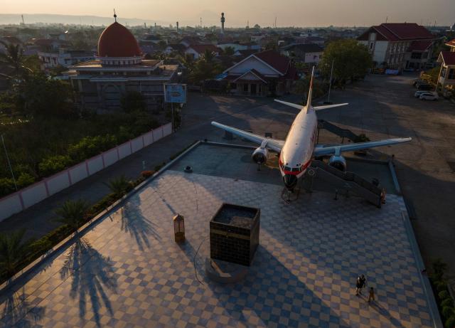 This aerial picture shows people standing next to a Boeing 737 mock-up installed at a Hajj pilgrimage centre in Banda Aceh on April 5, 2026. (Photo by CHAIDEER MAHYUDDIN / AFP)
