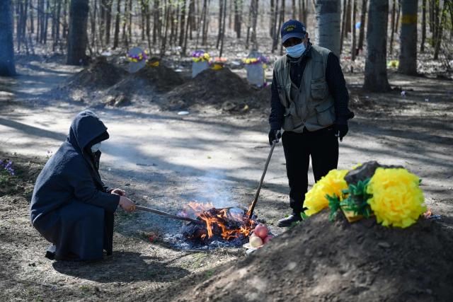 People burn paper to pay their respects at the grave of a family member during the annual tomb-sweeping festival, also known as the Qingming festival, near a village east of Beijing on April 5, 2026. (Photo by GREG BAKER / AFP)