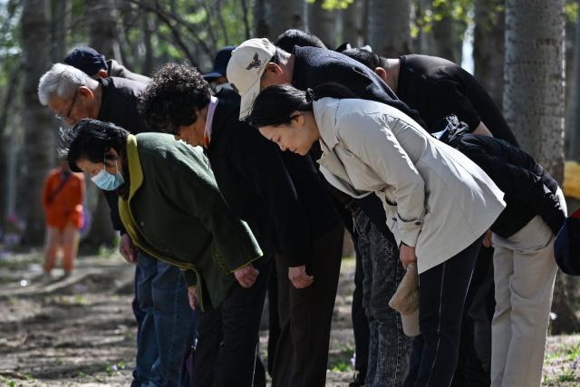 Family members bow to pay their respects at the grave of their ancestor during the annual tomb-sweeping festival, also known as the Qingming festival, near a village east of Beijing on April 5, 2026. (Photo by GREG BAKER / AFP)