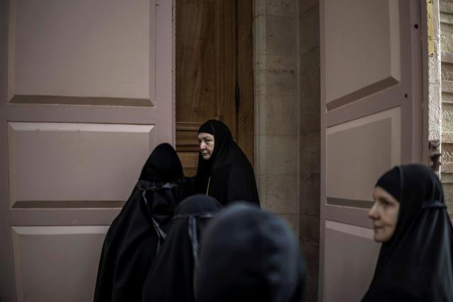 A group of Orthodox Christian nuns gather before entering a building near the entrance of the Church of the Holy Sepulchre, where the Latin Patriarch of Jerusalem will celebrate Easter Sunday Mass, behind closed doors due to the ongoing war, in the old city of Jerusalem on April 5, 2026. (Photo by MARCO LONGARI / AFP)