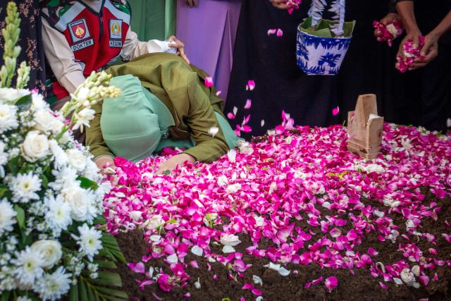 Fafa Nur Aziila (C), the widow of fallen Indonesian soldier and UN peacekeeper Farizal Rhomadhon, cries over his grave as family members scatter flower petals during his funeral at the Giripeni Heroes' Cemetery in Kulon Progo, Yogyakarta, on April 5, 2026. Farizal was one of three Indonesian soldiers killed while serving with the United Nations Interim Force in Lebanon (UNIFIL) in southern Lebanon, where Israel and Hezbollah have been fighting since Lebanon was drawn into the Middle East war. (Photo by DEVI RAHMAN / AFP)