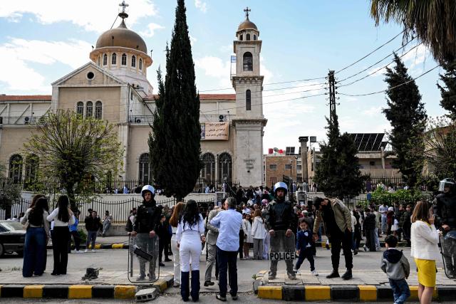 Syrian security forces stand guard outside as worshippers gather at the Greek Orthodox Church of the Holy Cross in the Qassaa district of Damascus on Orthodox Palm Sunday on April 5, 2026. (Photo by LOUAI BESHARA / AFP)