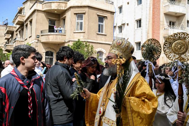 TOPSHOT - Bishop Romanos al-Hannat blesses Christian worshippers gathering at the Greek Orthodox Church of the Holy Cross in the Qassaa district of Damascus on Orthodox Palm Sunday on April 5, 2026. (Photo by LOUAI BESHARA / AFP)