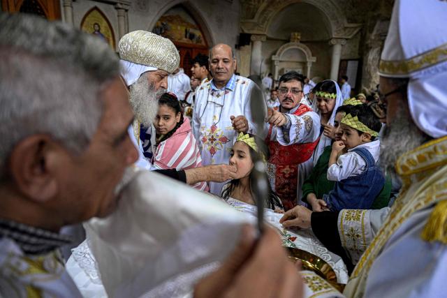 A Coptic Orthodox priest hands out communion to Christian worshippers attending mass at the Cave Church at the Coptic Orthodox Monastery of Simon the Tanner in the eastern hillside Mokkatam district of Cairo on Orthodox Palm Sunday on April 5, 2026. (Photo by Khaled DESOUKI / AFP)