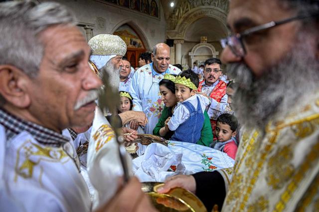 A Coptic Orthodox priest hands out communion to Christian worshippers attending mass at the Cave Church at the Coptic Orthodox Monastery of Simon the Tanner in the eastern hillside Mokkatam district of Cairo on Orthodox Palm Sunday on April 5, 2026. (Photo by Khaled DESOUKI / AFP)