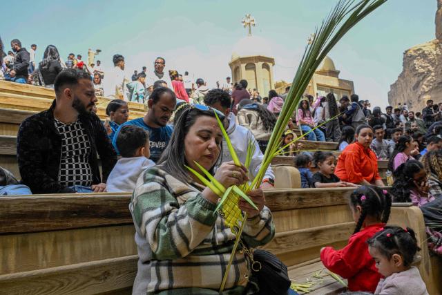 A Christian worshipper arranges a palm frond during mass at the Cave Church at the Coptic Orthodox Monastery of Simon the Tanner in the eastern hillside Mokkatam district of Cairo on Orthodox Palm Sunday on April 5, 2026. (Photo by Khaled DESOUKI / AFP)