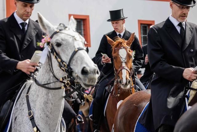 Sorbian horsemen dressed in traditional black attire sing as they ride on decorated horses during the Sorbian Easter horseback procession, on Easter Sunday, April 05, 2026 at the St Marienstern monastery in Panschwitz-Kuckau eastern Germany. This ancient religious ritual involves Sorbs riding decorated horses while singing to announce the resurrection of Jesus Christ. The Sorbs are a Slavic minority residing in eastern Germany near the German-Polish border. (Photo by JENS SCHLUETER / AFP)