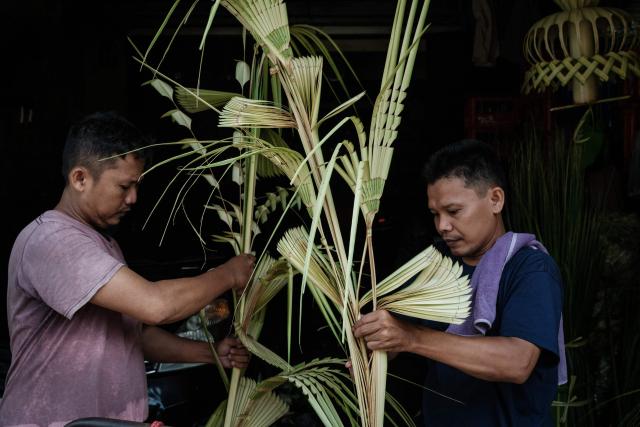 Men make decorative ornaments from leaves for a customer's birthday celebration in Jakarta on April 4, 2026. (Photo by YASUYOSHI CHIBA / AFP)