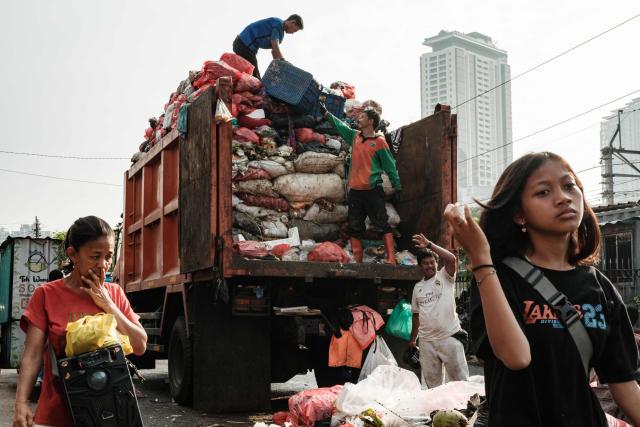 Workers load trash from a street in Jakarta on April 4, 2026. (Photo by YASUYOSHI CHIBA / AFP)