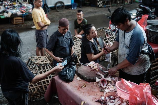 A butcher cuts up a chicken for a customer in Jakarta on April 4, 2026. (Photo by YASUYOSHI CHIBA / AFP)