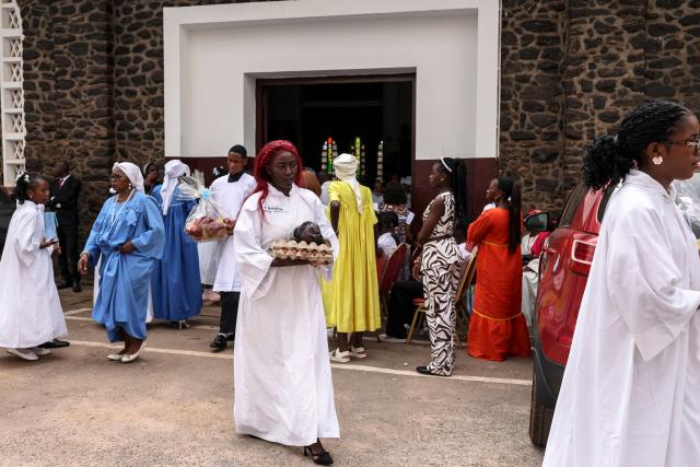 Worshippers carry offerings during Easter Mass at Notre Dame des Victoires Cathedral in Yaounde on April 5, 2026. (Photo by Daniel BELOUMOU OLOMO / AFP)